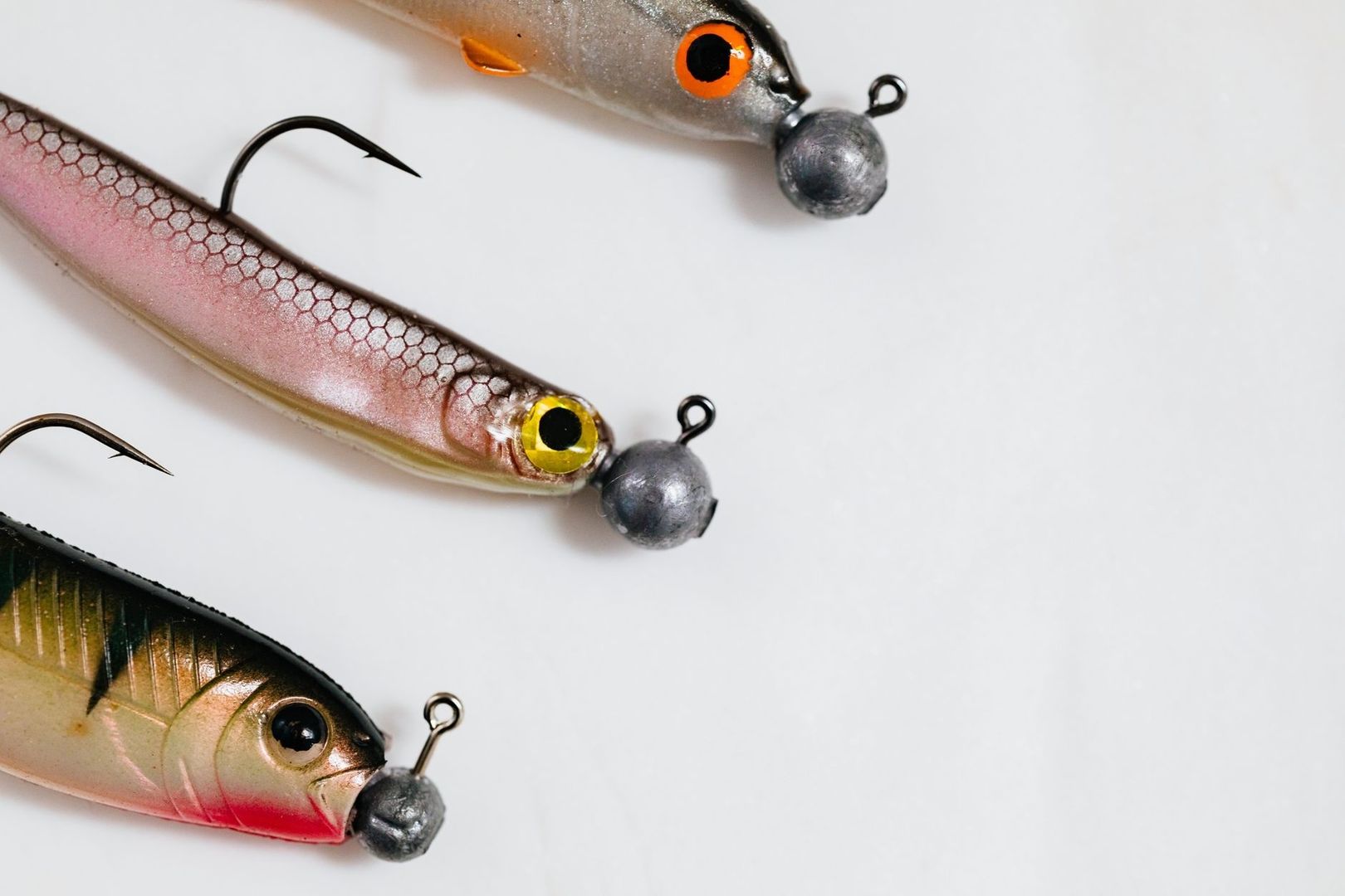 Three soft-plastic fishing lures with jig heads and exposed hooks