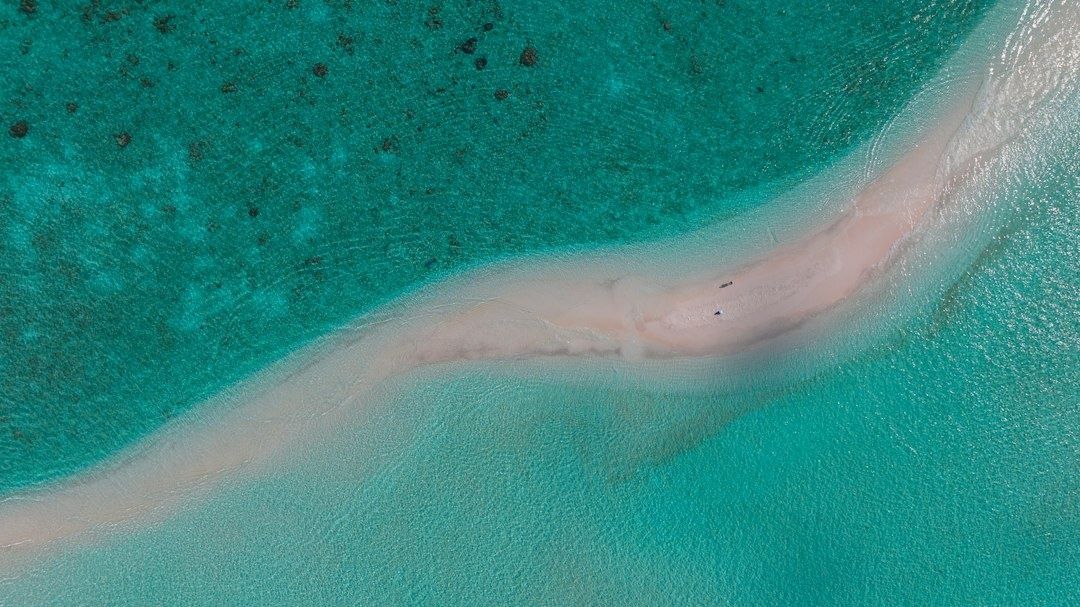 Aerial view of a pale sandbar winding through turquoise shallow water