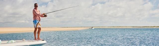 Angler casting from a paddleboard across a shallow coastal flat