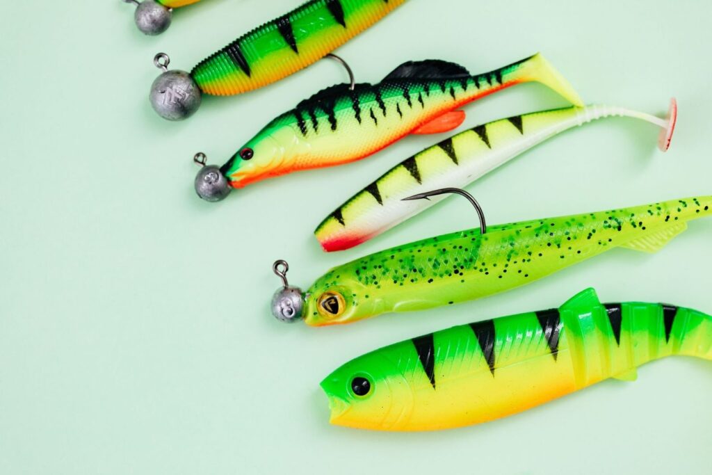 Colorful soft-plastic fishing lures and jig heads arranged on a pale surface