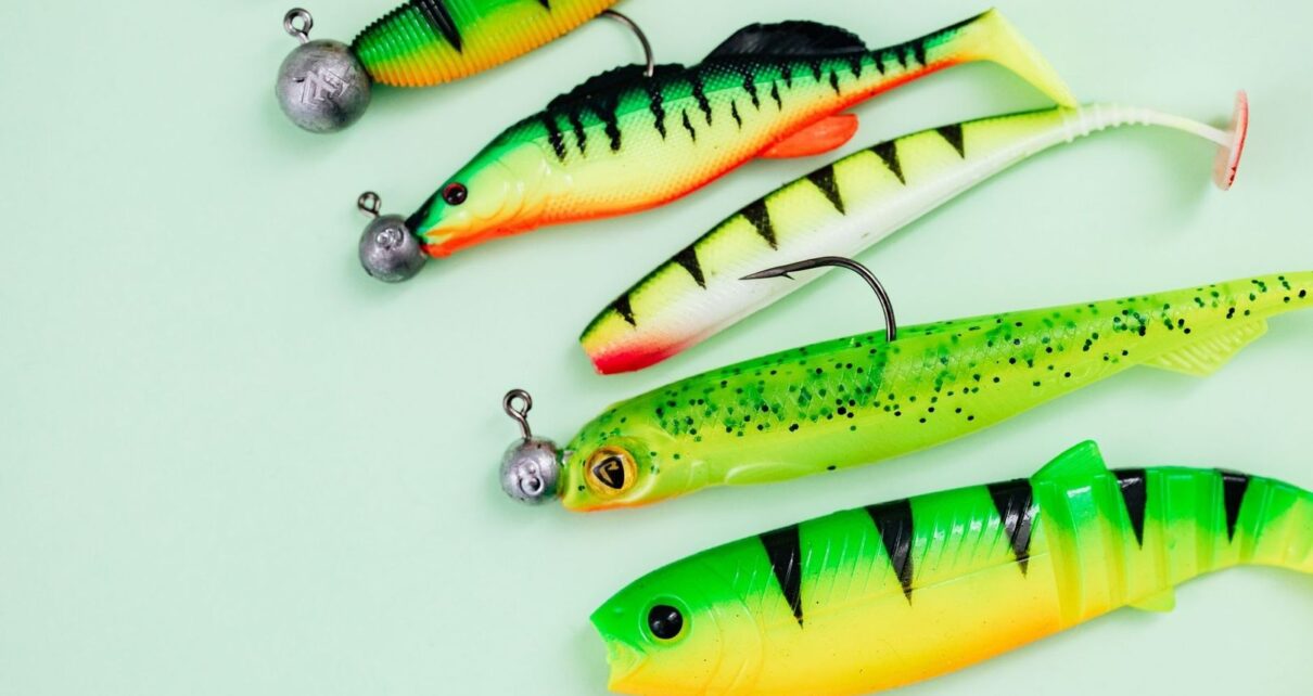Colorful soft-plastic fishing lures and jig heads arranged on a pale surface